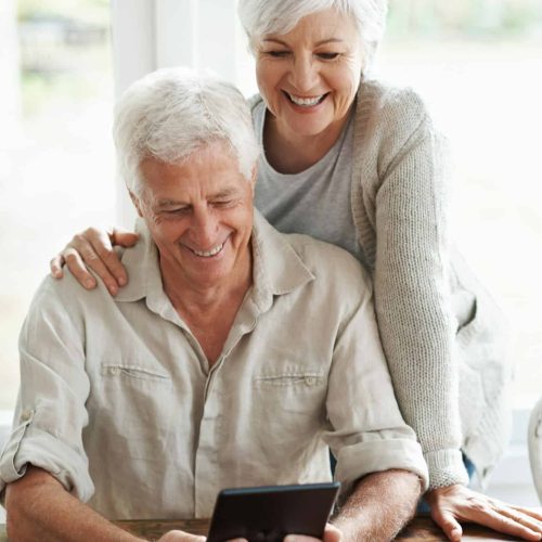 A senior couple examining a digital tablet as they sit at they dining room table A senior couple examining a digital tablet as they sit at they dining room table