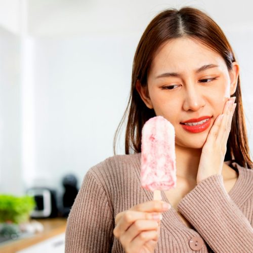 Asian woman has gotten tooth sensitivity before eating ice cream