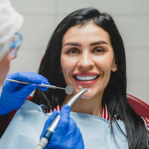 Orthodontist applying veneers, whitening her teeth, filling tooth, curing caries decay. Stomatology Orthodontist applying veneers, whitening her teeth, filling tooth, curing caries decay. Stomatology